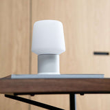 Witte draadloze tafellamp van sackit op een houten tafel met zachte lampenkap en ronde voet passend bij een modern Scandinavisch interieur