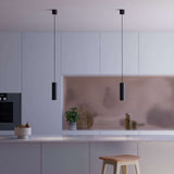 Twee zwarte Expo hanglampen boven een kookeiland in een modern interieur met zachte roze achterwand van sackit