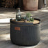 Ronde donkere buitenpoef met teak dienblad en decoratie op een terras. Een stijlvolle outdoor oplossing van sackit voor serveren en ontspannen.