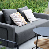 Grijze modulaire loungesofa voor buiten met zachte kussens op een terras tussen groen en tuinmeubilair in Scandinavische stijl