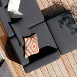 Donkergrijze modulaire loungesofa voor buiten op een houten terras met zachte kussens en een kleurrijk sierkussen in Scandinavische stijl