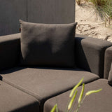 Close up van een donkerbruine hoekmodule van de sackit Cobana loungesofa met zacht rugkussen en brede zitkussens in een duinrijke buitenomgeving