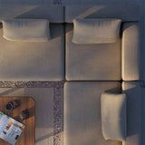 Overzicht van een modulaire outdoor hoekbank in taupe met zachte kussens en een houten bijzettafel in warm avondlichtlamaanka
