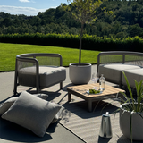 Modulaire Kirra loungesofa voor twee personen van sackit in een zonnige tuin met bijpassende fauteuils salontafel planten en zachte kussens
