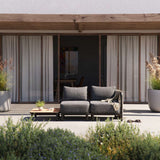 Donkergrijze modulaire loungesofa van sackit op een modern terras met zachte kussens en plaid tussen planten en een eigentijdse woning in Denemarken ontworpen