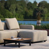 Beige modulaire loungesofa voor buiten met zachte kussens en lage salontafel op een terras aan het water in een natuurlijke omgeving