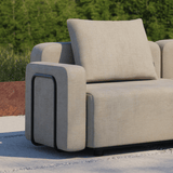 Beige armleuning van de sackit Cobana loungesofa met zacht kussen buiten op een terras tegen een groene achtergrond