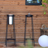 Twee zwarte buitenstandaards van sackit met een wijnkoeler tegen een houten wand in een sfeervolle tuinomgeving met planten en buitenverlichting