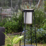 Zwarte buitenstandaard van sackit met roestvrijstalen wijnkoeler in een groene tuin tussen bloeiende planten en tuinmeubelen