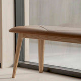 Bruine leren bank met een glad eikenhouten frame en schuine poten in een lichte ruimte. Scandinavisch design van sackit voor comfortabel zitten.