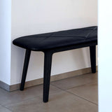 Zwarte bank met zachte leren zitting en donkere houten poten in een modern interieur van sackit. Deens design voor comfortabel zitten.