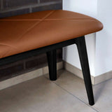 Detail van een bruine leren nordic bank van sackit met zachte bekleding en zwarte houten poten in een modern interieur