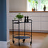 Zwarte serveertafel op wielen met twee ronde bladen in een moderne keuken met een plant en kruidenmolens als decoratie van sackit