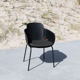 Zwarte Patio stoel met donker zitkussen op een licht terras naast duingras voor comfortabel buiten zitten van sackit ontworpen voor Scandinavisch weer
