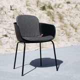 Zwarte patio stoel met volledig grijs kussen van sackit op een terras bij de duinen voor comfortabel buiten zitten