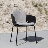 Zwarte buitenstoel met lichtgrijs zitkussen op een terras in de duinen voor comfortabel buiten zitten en een modern Scandinavisch ontwerp