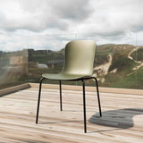 Olijfgroene buitenstoel van sackit met ergonomische zitting en zwart metalen onderstel op een houten terras met uitzicht op duinen en bewolkte lucht