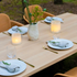 sackit eikenhouten eettafel gedekt met witte borden linnen servetten glazen bestek kaarsen en een vaas met groen in een natuurlijke buitenomgeving