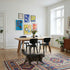 Eikenhouten eettafel in een lichte eetkamer met zwarte stoelen kleurrijk vloerkleed planten en een kat in een stijlvol Scandinavisch interieur