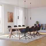 Zwarte draaibare eetkamerstoelen van sackit rond een houten eettafel in een Scandinavisch interieur met vloerkleed en zachte verlichting