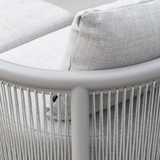 Close up van een lichtgrijze modulaire loungesofa met geweven kussens en verticale koorden rond een afgerond frame voor stijlvol buitencomfort