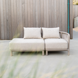 Lichtbeige tweezits loungesofa van sackit voor buiten met zachte kussens en open zijkant tegen een houten wand op een modern terras