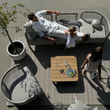 Modulaire grijze loungesofa van sackit in een Deens ontworpen buitenruimte met gezin en kinderen rond een houten tafel op het terras