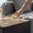 Teakhouten opbergtafel van sackit naast een grijze loungesofa met een glas water en citroen op het tafelblad voor buitengebruik