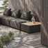 Donkere modulaire loungesofa op een houten terras met een salontafel voor buiten met houten blad en praktische opbergruimte naast zachte rugkussens