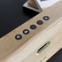 Detailfoto van een eikenhouten Move Wood speaker van sackit met zwarte bedieningsknoppen en een ovale opening voor helder geluid