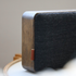 Detail van een houten speaker met afgeronde eikenhouten rand en zwarte stoffen bekleding van sackit in een stijlvol Scandinavisch ontwerp