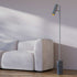Grijze Expo vloerlamp van sackit met matte cilindrische lampenkop en marmeren voet naast een lichte bank in een stijlvol Scandinavisch interieur