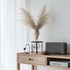 Donkergrijze Move 150 speaker van sackit op een houten dressoir in een licht Scandinavisch interieur met vaas en pampasgras