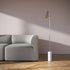 sackit vloerlamp met slank aluminium profiel en marmeren voet naast een zachte bank in een modern interieur met houten vloer en warme verlichting