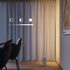 Slanke vloerlamp van sackit met warm verticaal licht langs de wand en een rustige marmeren voet in een stijlvol interieur met eetkamerstoelen