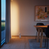 Slanke vloerlamp met warm verticaal licht langs de wand en een massieve marmeren voet in een stijlvol Scandinavisch interieur naast de eettafel