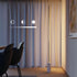 sackit Expo 185 vloerlamp met slank aluminium profiel en marmeren voet die warm verticaal licht langs een gordijnwand verspreidt in een modern interieur