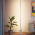 Slanke aluminium vloerlamp met marmeren voet van sackit naast een plant in een warm modern interieur met zacht verticaal licht langs de wand