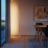 Slanke Expo 185 vloerlamp van sackit met warm verticaal licht langs de wand en een marmeren voet in een modern interieur naast een houten eettafel