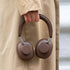 Bruine Touch 310 over ear hoofdtelefoon van sackit in de hand van een persoon met een beige jas en comfortabele oorkussens
