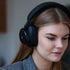 Vrouw met een zwarte Touch 400 over ear hoofdtelefoon van sackit tijdens een rustig moment binnenshuis en genietend van persoonlijke audio luisterervaring