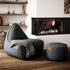 Grijze canvas lounge chair van sackit met bijpassende poef in een sfeervol interieur met haard en houten vloer