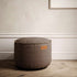 Bruine ronde canvas poef van sackit voor binnen met decoratieve stikrand in een stijlvol Scandinavisch interieur