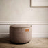 Ronde taupekleurige canvas poef van sackit voor comfortabel zitten in een stijlvol Scandinavisch interieur met zachte bekleding en decoratieve stikrand
