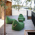 Drie groene weerbestendige zitzakken op een houten terras, geschikt als comfortabele loungestoelen voor buiten in een moderne tuinomgeving