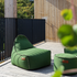 Groene weerbestendige zitzak van sackit met bijpassende poef op een houten terras voor comfortabel loungen in de buitenlucht
