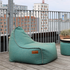 Turquoise weerbestendige outdoor zitzak van sackit op een houten balkon met stadszicht en een plantenbak voor ontspannen loungen in de buitenlucht