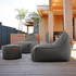 Donkergrijze Cobana lounge chairs met bijpassende poef op een houten terras buiten bij een modern huis van sackit voor ontspannen Scandinavisch buitenleven