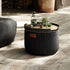 Zwarte Cobana poef van sackit met houten dienblad op een houten terras. Weerbestendige outdoor poef als voetensteun of extra zitplaats