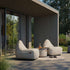 Lichte Cobana poef tussen twee comfortabele loungestoelen op een terras bij een modern huis van sackit voor ontspannen buiten zitten